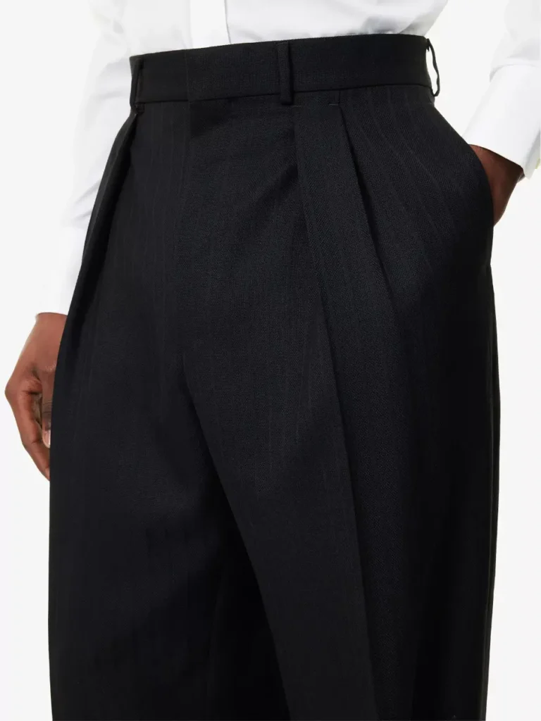 Front view of a male model wearing Tom Ford black pleated wide-leg wool trousers styled with a tucked-in crisp white dress shirt.